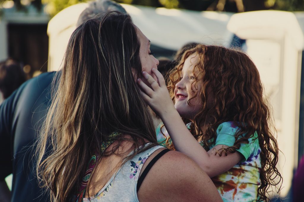 woman-carrying-girl-while-showing-smile