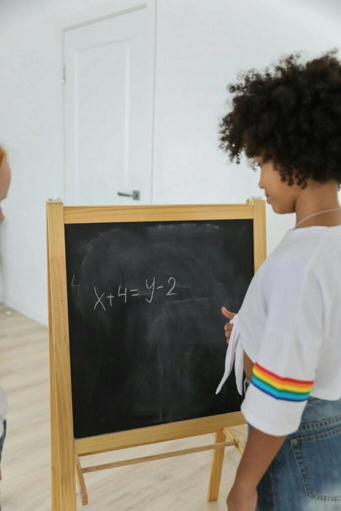a child writes math equations on a chalkboard
