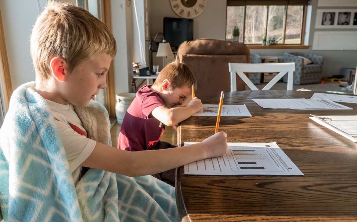 two young boys doing homework at a kitchen table