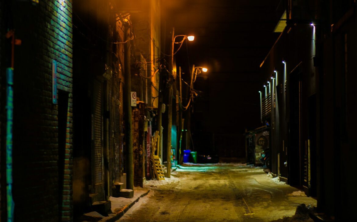 Narrow urban alley illuminated by warm streetlights at night